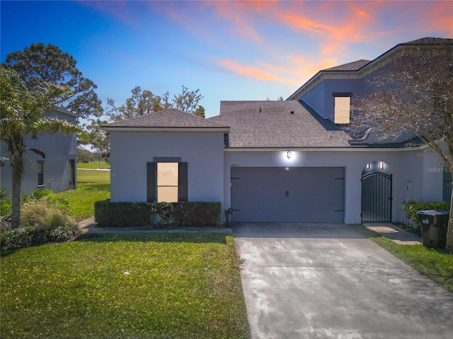 view of front of house with a gate, a yard, stucco siding, concrete driveway, and a garage