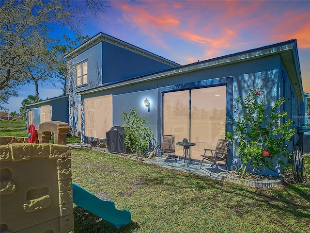 back of property with a patio, a yard, and stucco siding