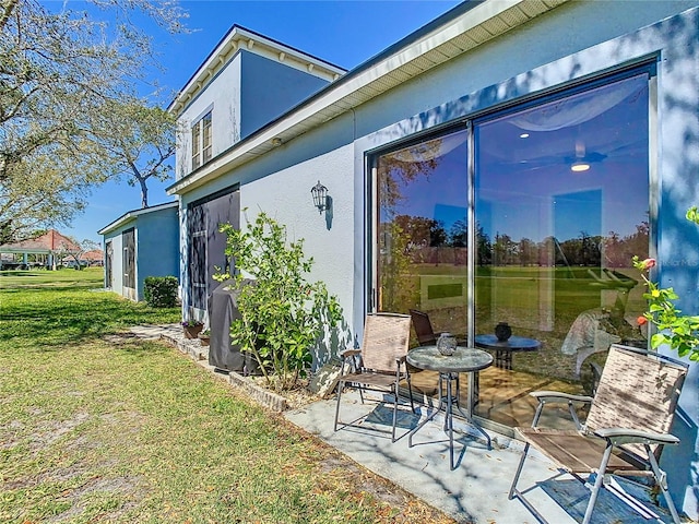 view of side of property featuring a patio, a lawn, and stucco siding