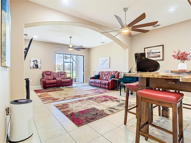 living area featuring arched walkways, light tile patterned floors, recessed lighting, and ceiling fan