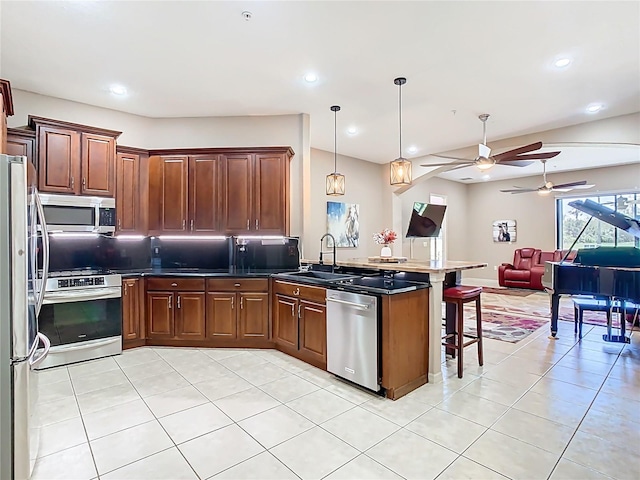 kitchen featuring open floor plan, a breakfast bar area, appliances with stainless steel finishes, a peninsula, and a sink