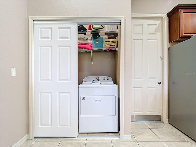 washroom with light tile patterned floors, baseboards, washer / dryer, and laundry area