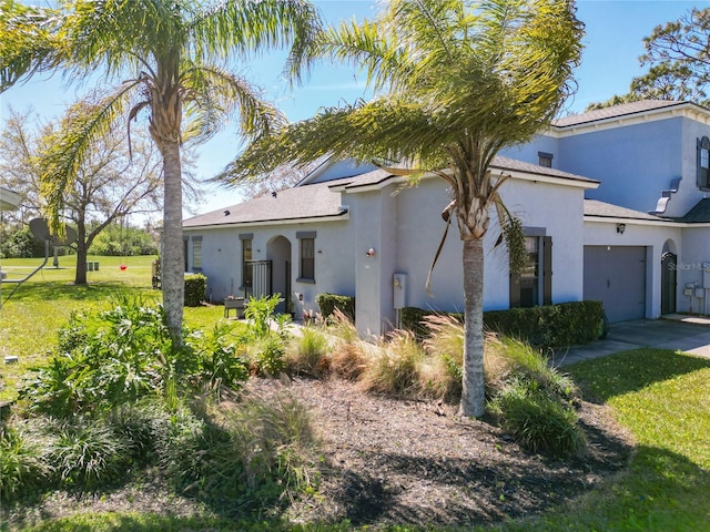 view of front of home with a front yard, driveway, and stucco siding