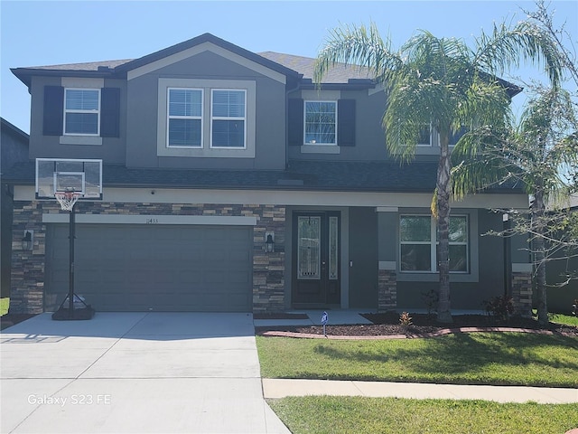 view of front of property with stone siding, a front lawn, concrete driveway, and stucco siding