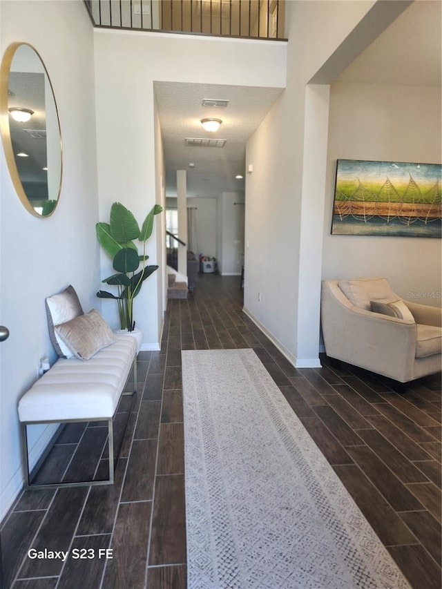 hallway with wood tiled floor, visible vents, stairway, and baseboards