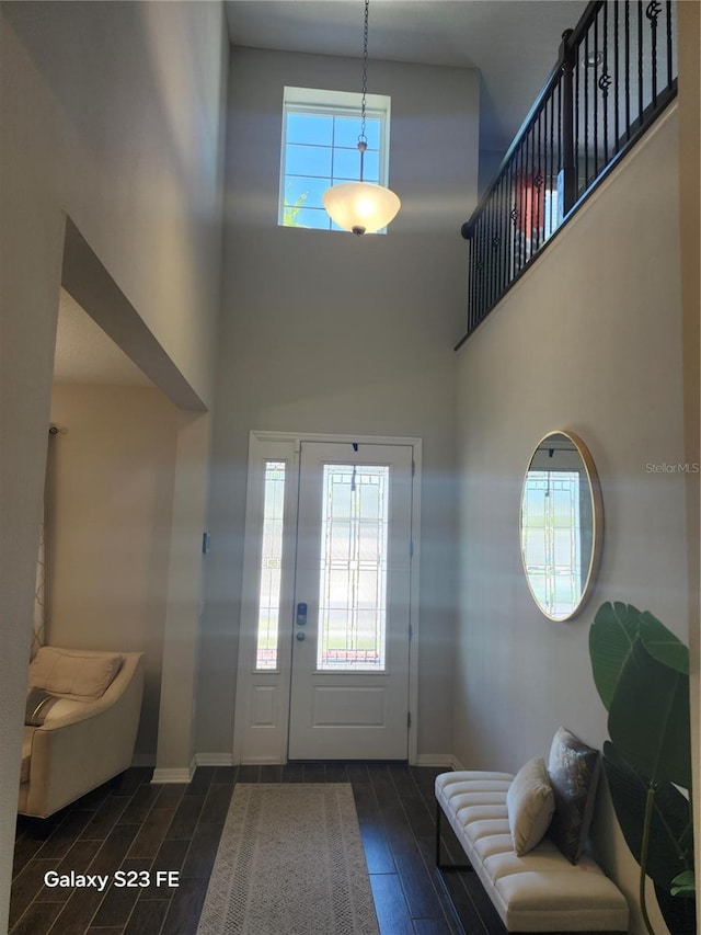 foyer featuring wood tiled floor, a high ceiling, and baseboards