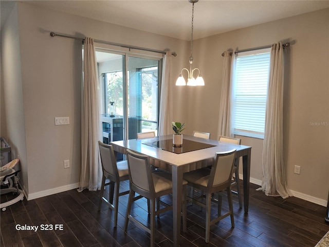 dining space featuring wood tiled floor, baseboards, a chandelier, and a wealth of natural light