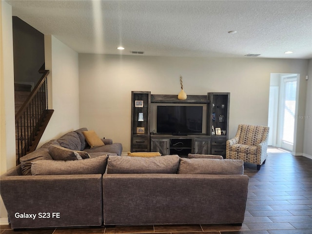 living area with dark wood-type flooring, visible vents, a textured ceiling, and stairs