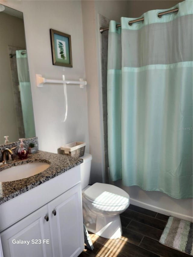 full bathroom with wood tiled floor, shower / bathtub combination with curtain, toilet, and vanity