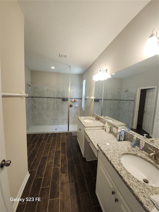 bathroom featuring a walk in shower, visible vents, wood finish floors, and vanity