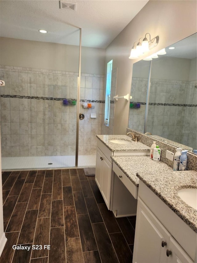 full bathroom with wood tiled floor, visible vents, walk in shower, and vanity