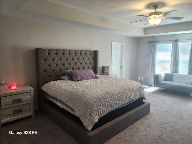 bedroom featuring carpet floors, ceiling fan, a tray ceiling, and a textured ceiling