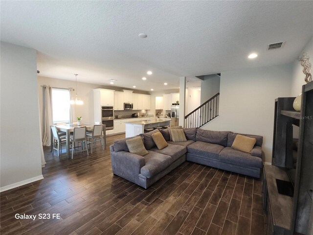 living room featuring stairs, dark wood finished floors, visible vents, and recessed lighting