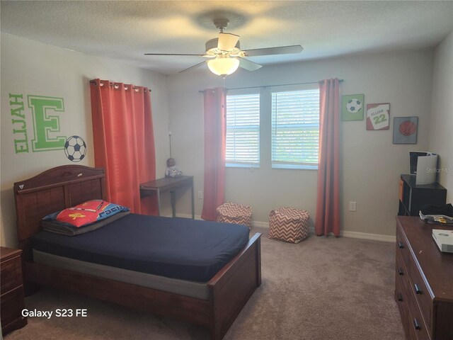 carpeted bedroom with ceiling fan, a textured ceiling, and baseboards