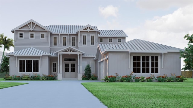 view of front of home featuring a front yard, driveway, a standing seam roof, an attached garage, and metal roof