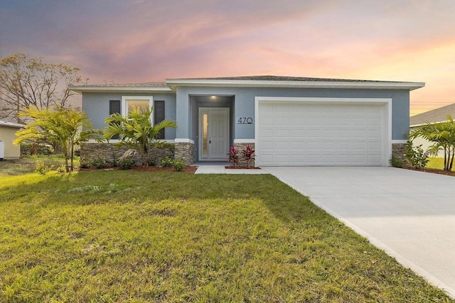 view of front of property featuring driveway, a lawn, stone siding, an attached garage, and stucco siding