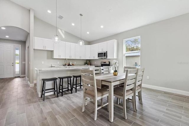 dining space with wood tiled floor, visible vents, arched walkways, and baseboards