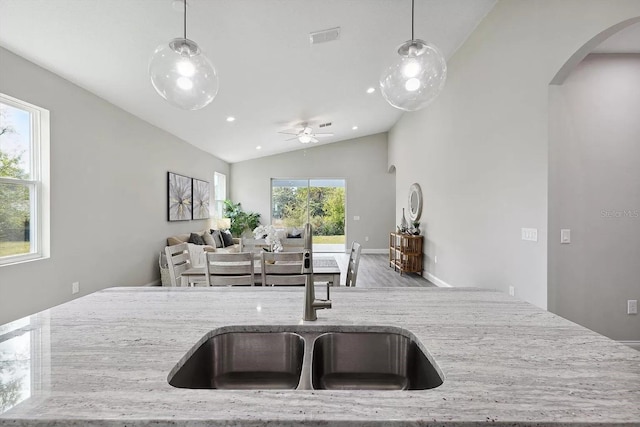 kitchen featuring arched walkways, light stone counters, open floor plan, and visible vents