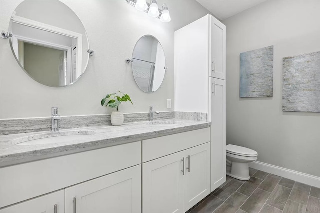 full bathroom with wood finish floors, a sink, toilet, and baseboards