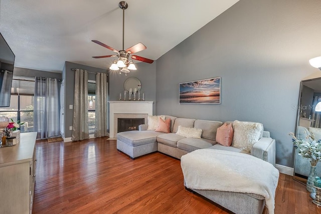 living room featuring a fireplace, wood finished floors, a ceiling fan, and baseboards