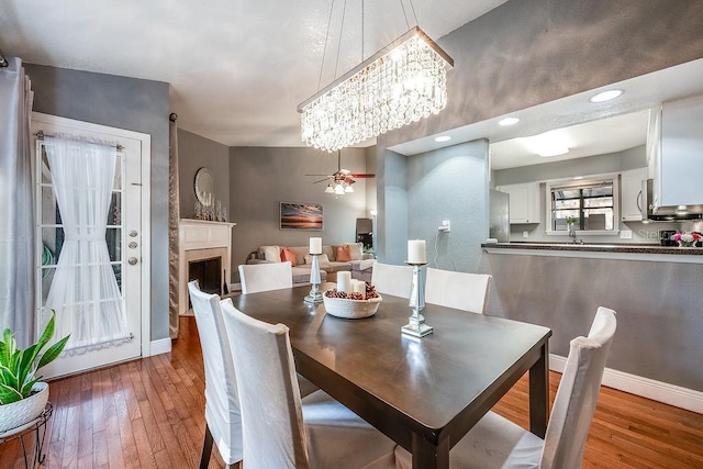 dining room with a fireplace, hardwood / wood-style flooring, and baseboards