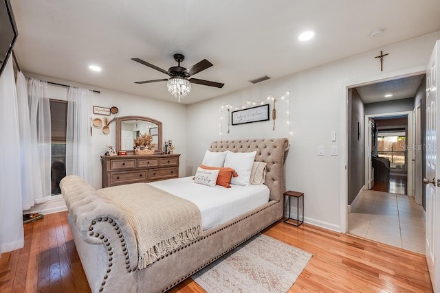 bedroom featuring visible vents, ceiling fan, baseboards, and wood finished floors