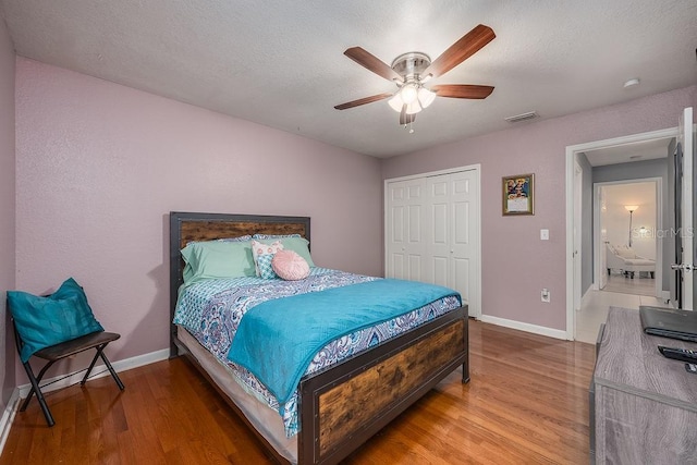 bedroom with baseboards, a closet, visible vents, and wood finished floors