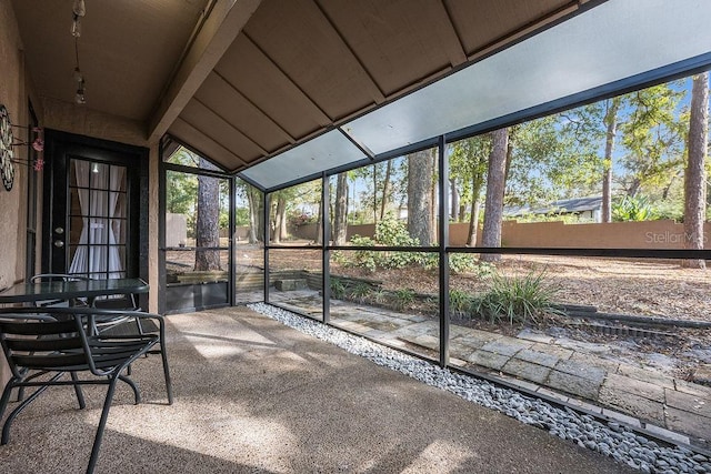 unfurnished sunroom featuring vaulted ceiling with beams