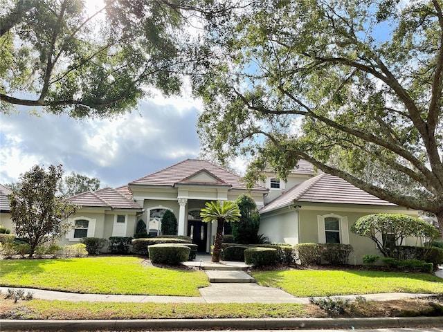 view of front of property with stucco siding, a tiled roof, and a front yard