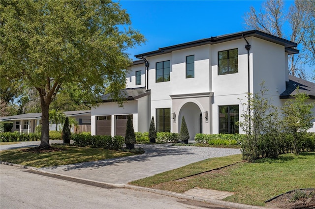 view of front of property with stucco siding, decorative driveway, and a front yard