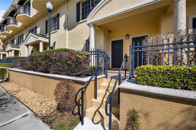 doorway to property with fence and stucco siding