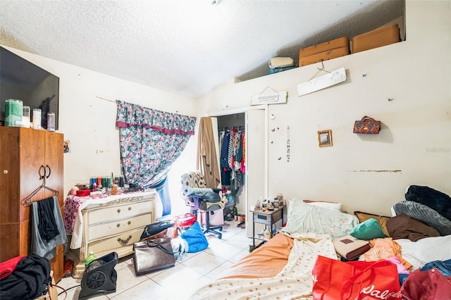 tiled bedroom with a closet, a textured ceiling, and lofted ceiling