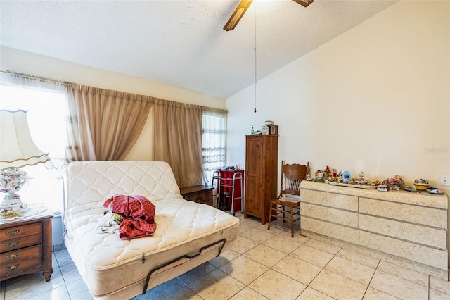 bedroom featuring a textured ceiling, light tile patterned flooring, a ceiling fan, and vaulted ceiling