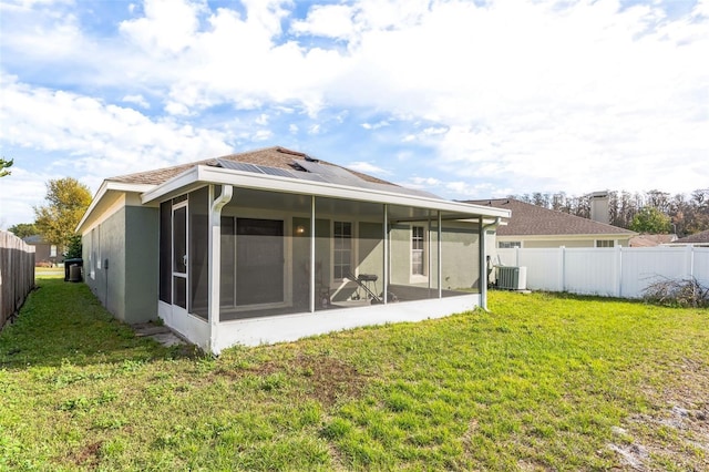 rear view of property featuring central air condition unit, a lawn, a fenced backyard, and a sunroom