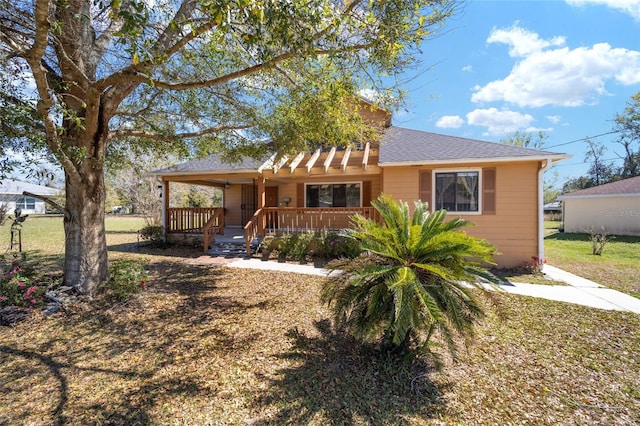 view of front facade featuring roof with shingles, covered porch, and a front lawn