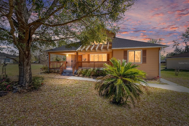 view of front of property featuring covered porch, a shingled roof, and a front yard