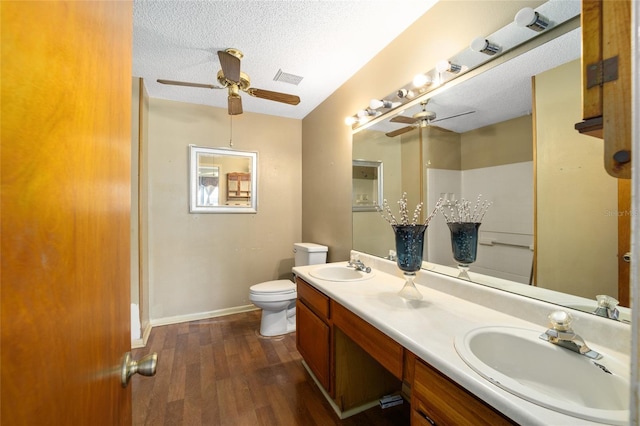 bathroom with toilet, wood finished floors, a textured ceiling, a ceiling fan, and a sink