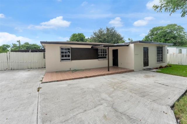 view of front of house with a patio area, fence, and stucco siding