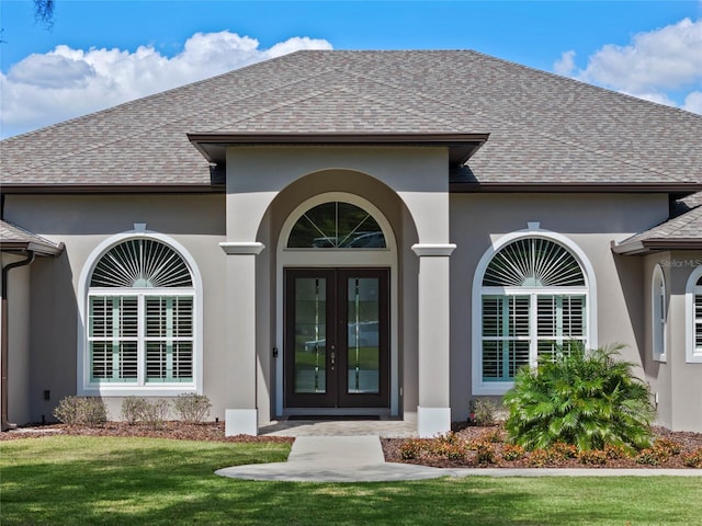 entrance to property featuring french doors, roof with shingles, and stucco siding