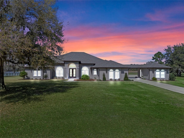 view of front of property with driveway, fence, french doors, a front yard, and stucco siding