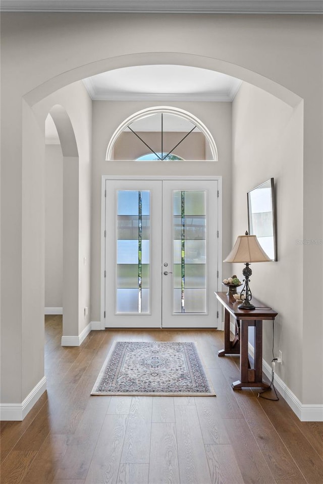 foyer entrance with ornamental molding, french doors, wood-type flooring, and baseboards