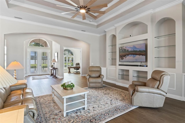 living room featuring built in shelves, visible vents, arched walkways, and wood finished floors