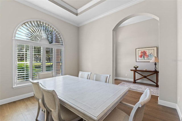 dining space with ornamental molding, arched walkways, baseboards, and wood finished floors