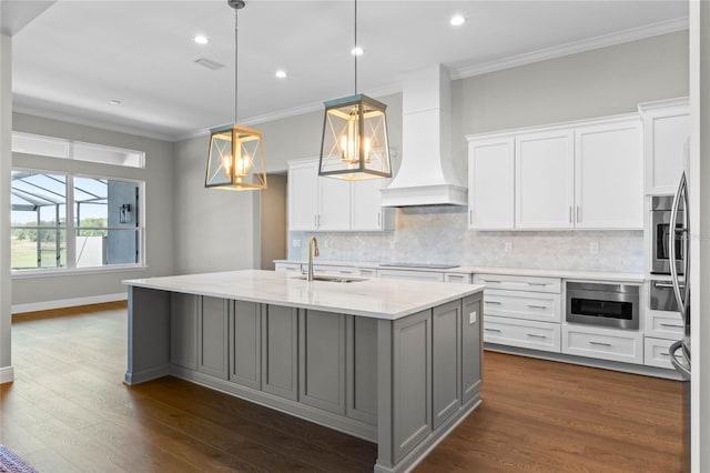 kitchen featuring tasteful backsplash, custom range hood, dark wood-style flooring, crown molding, and a sink