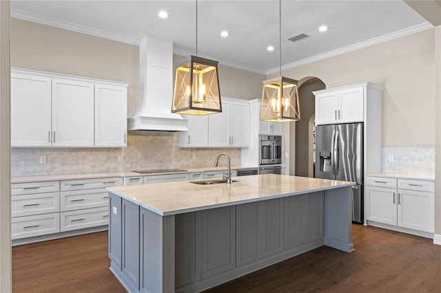 kitchen featuring stainless steel fridge, visible vents, black electric cooktop, premium range hood, and a sink