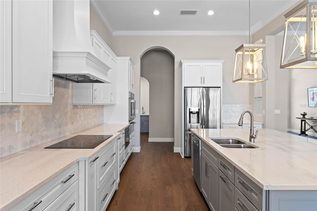 kitchen featuring arched walkways, a sink, visible vents, appliances with stainless steel finishes, and custom exhaust hood