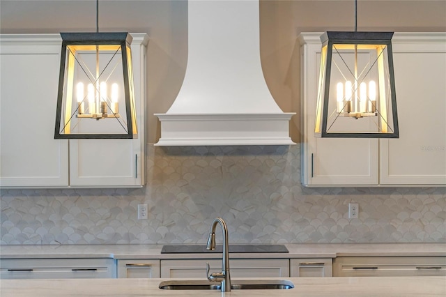 kitchen featuring backsplash, custom exhaust hood, a chandelier, and a sink