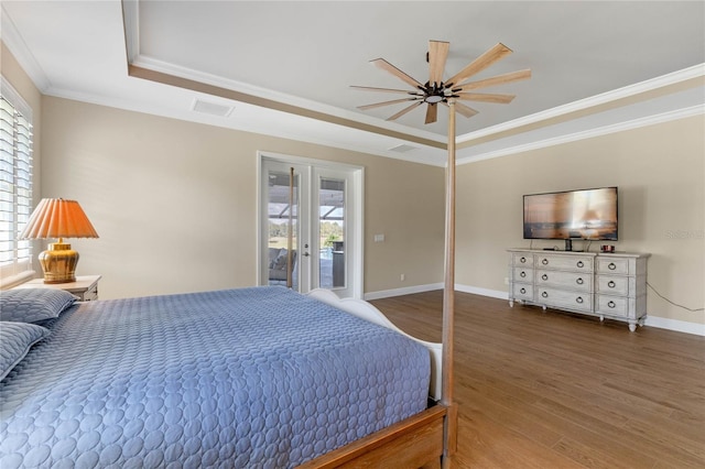 bedroom featuring french doors, crown molding, a raised ceiling, wood finished floors, and baseboards