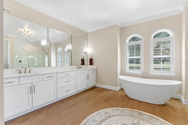 bathroom with wood finished floors, a sink, a marble finish shower, and crown molding