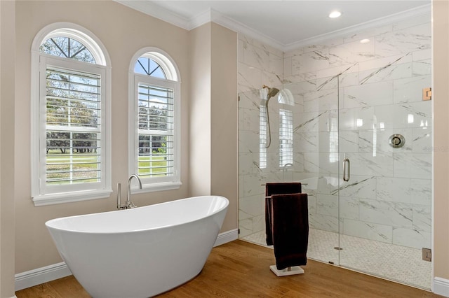 bathroom featuring a freestanding bath, ornamental molding, a stall shower, wood finished floors, and baseboards